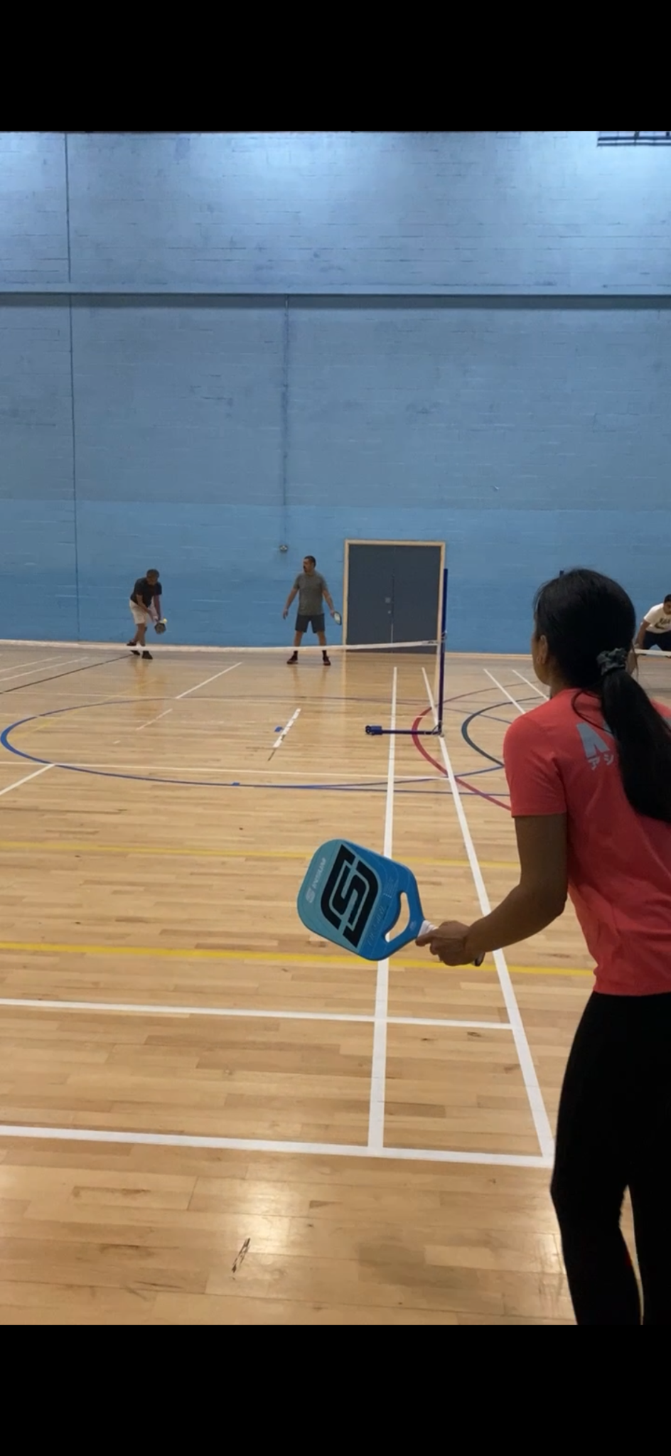 Kush’s wife waiting with her paddle as his dad serves in the early Harrow sessions