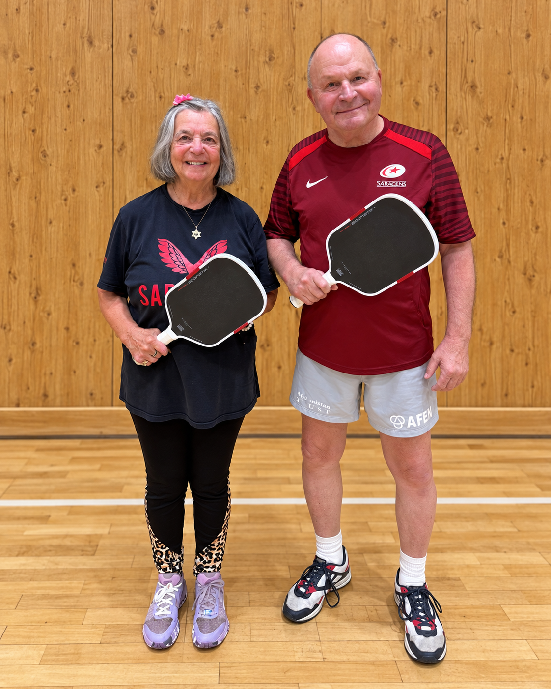 Susie and Steve holding their Boomstik-style pickleball paddles